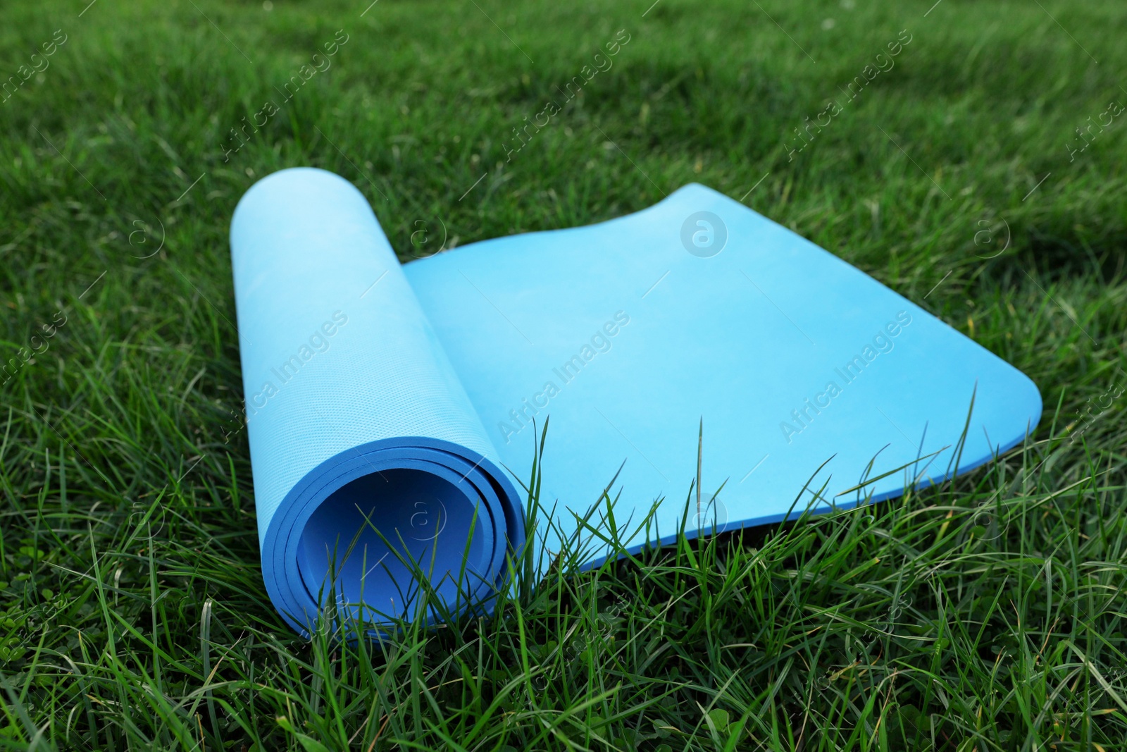 Photo of Blue karemat or fitness mat on fresh green grass outdoors