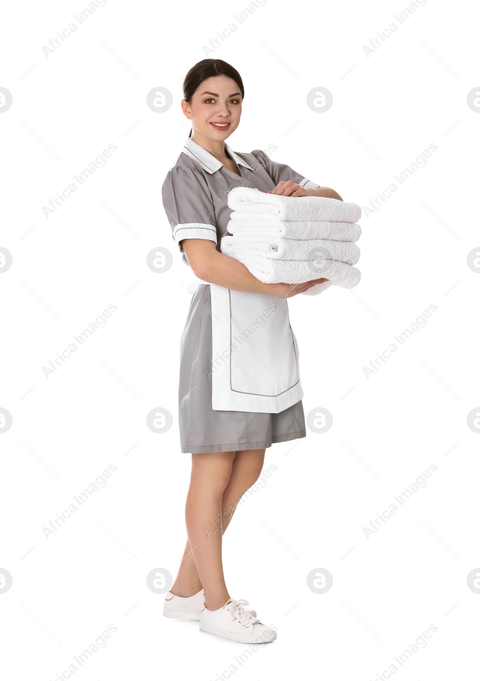 Photo of Young chambermaid holding stack of fresh towels on white background