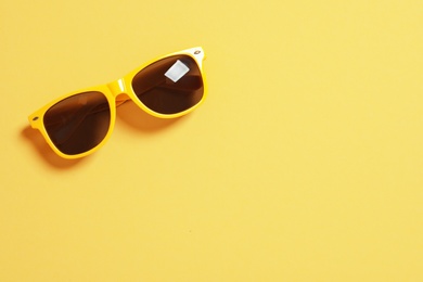 Stylish sunglasses on color background, top view with space for text. Beach accessories