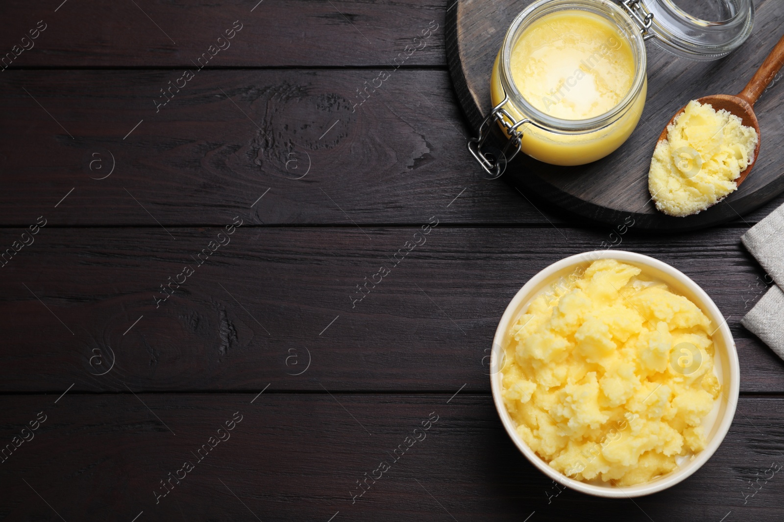 Photo of Ghee butter in dishware on wooden table, flat lay. Space for text