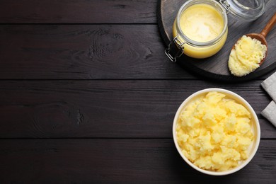 Ghee butter in dishware on wooden table, flat lay. Space for text