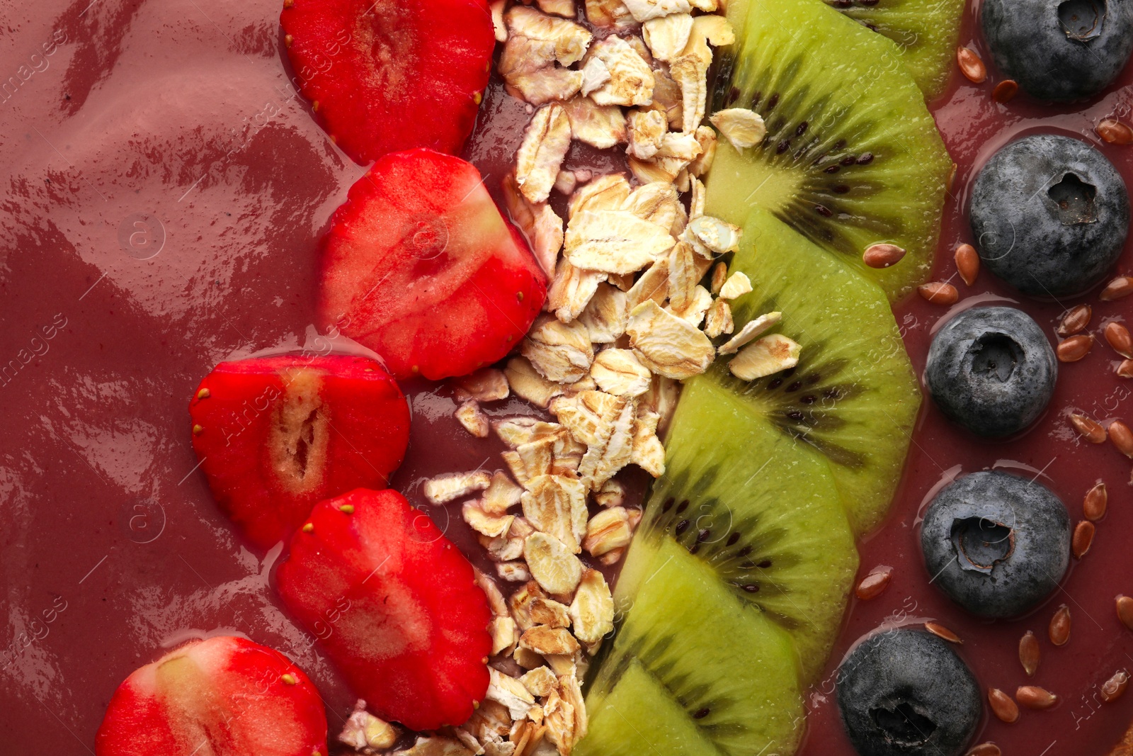 Photo of Delicious smoothie with fresh blueberries, strawberries, kiwi slices and oatmeal, top view