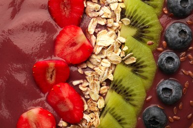 Photo of Delicious smoothie with fresh blueberries, strawberries, kiwi slices and oatmeal, top view