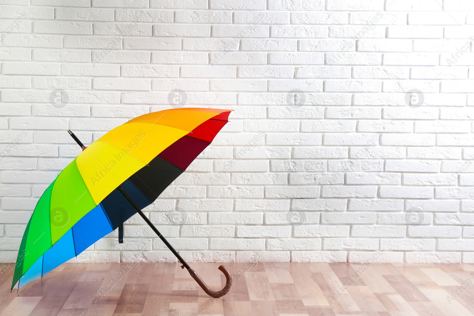 Photo of Beautiful colorful umbrella near white brick wall. Space for text
