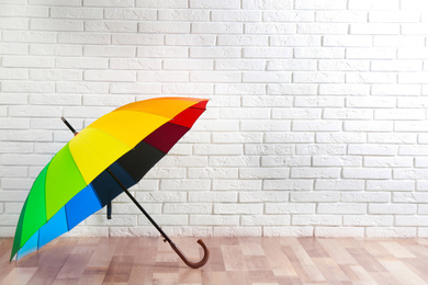 Beautiful colorful umbrella near white brick wall. Space for text