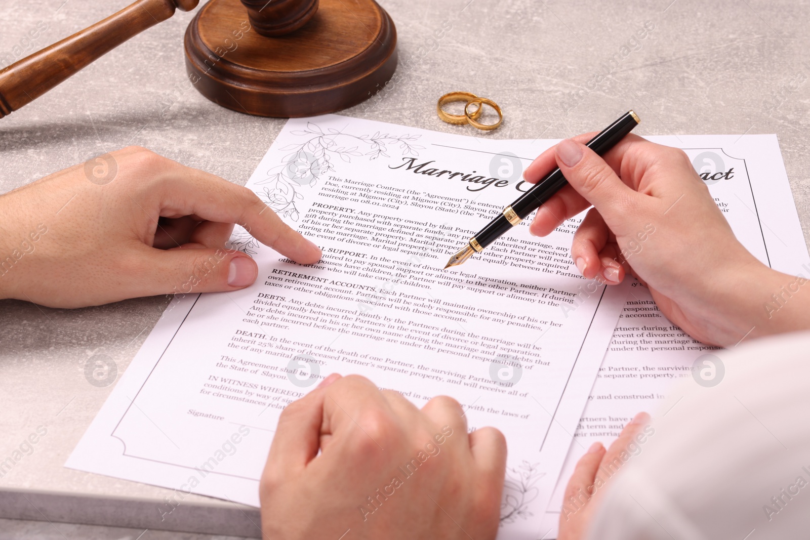 Photo of Man and woman signing marriage contract at light grey table, closeup