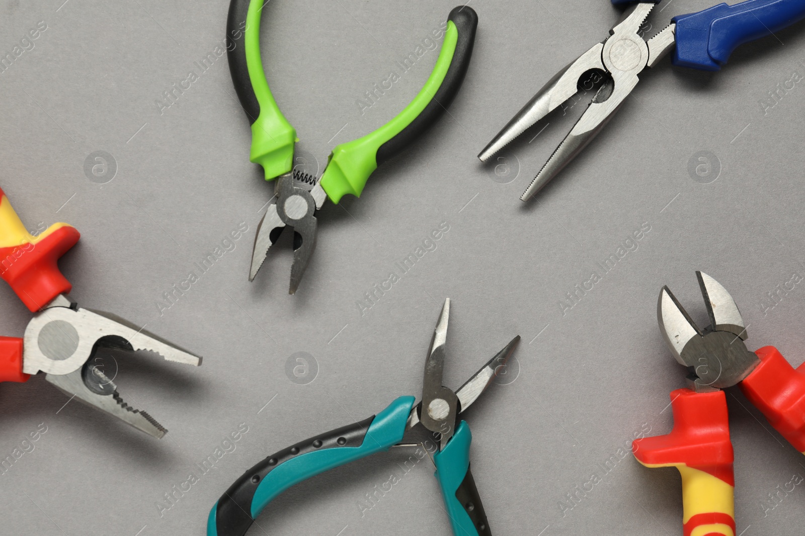 Photo of Different pliers on grey background, flat lay