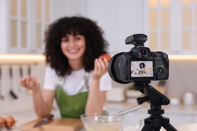 Photo of Food blogger recording video in kitchen, focus on camera