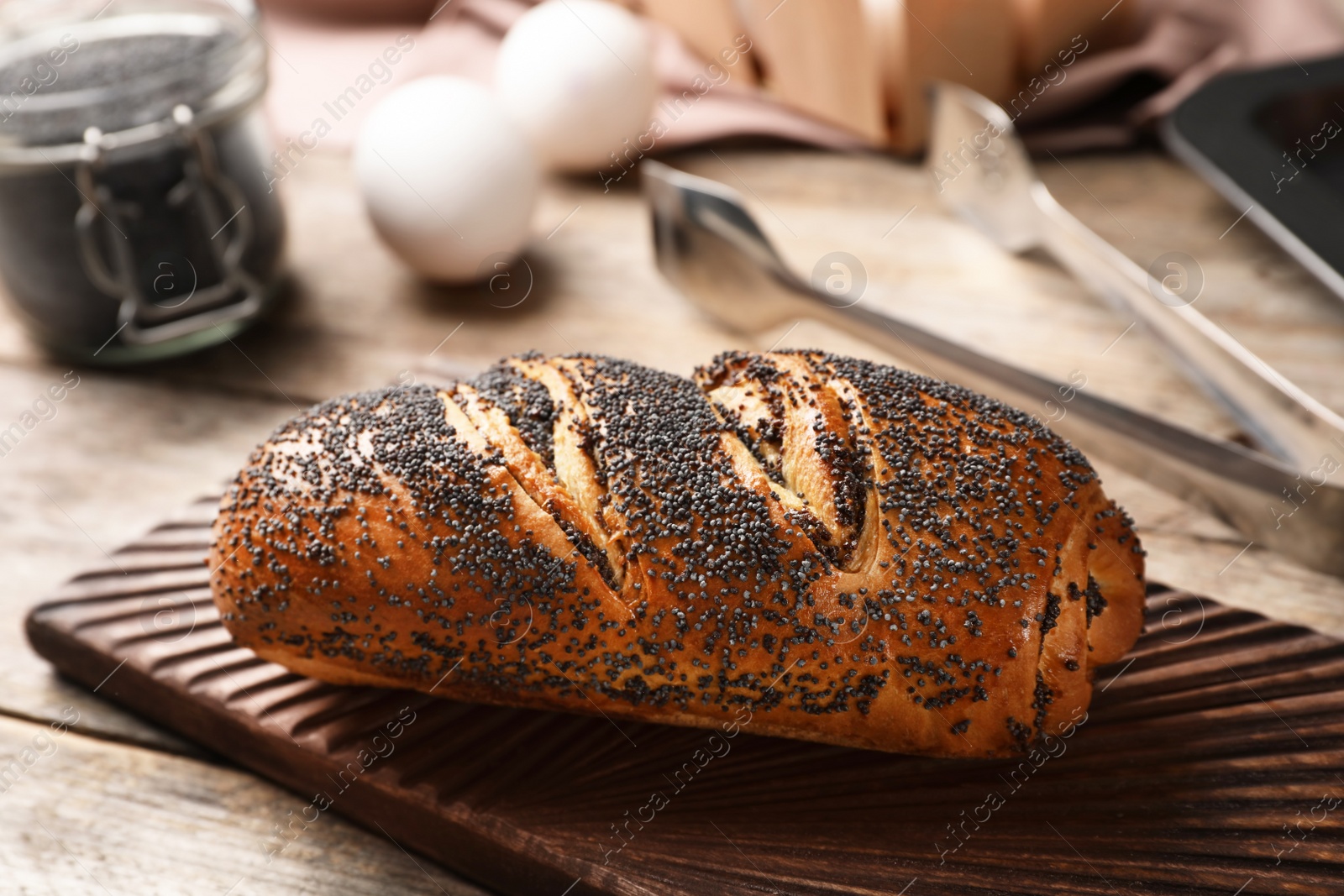 Photo of Board with freshly baked poppy seed roll on table