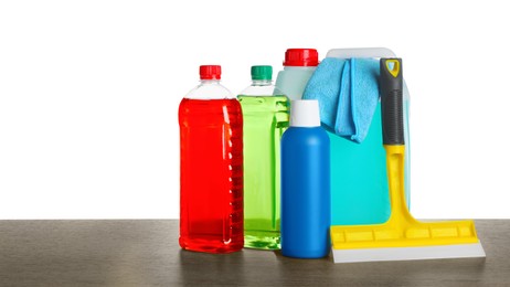 Photo of Bottles, squeegee and car wash cloth on wooden table against white background