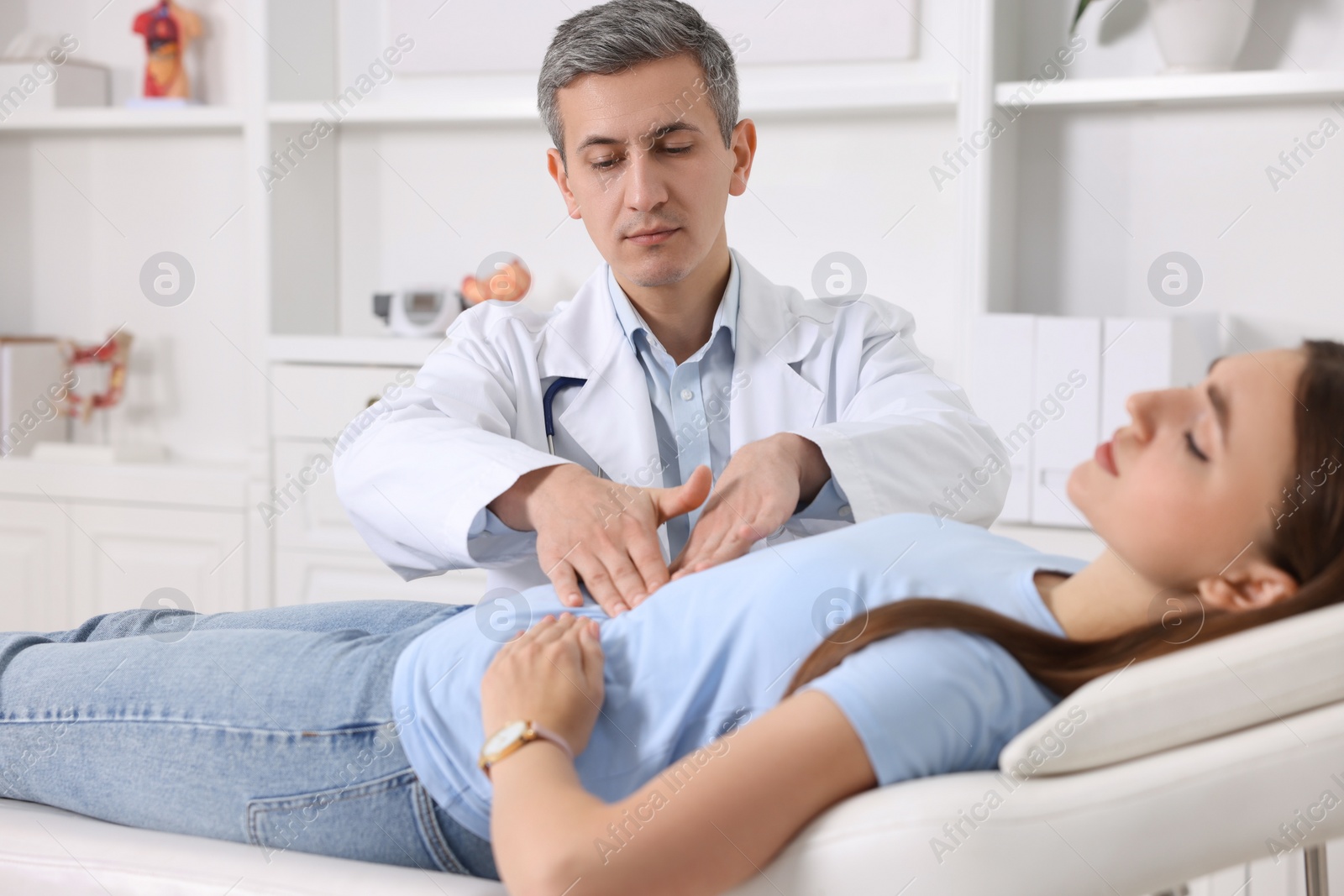 Photo of Gastroenterologist examining patient with stomach pain on couch in clinic