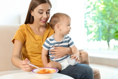 Woman feeding her child on couch indoors. Healthy baby food