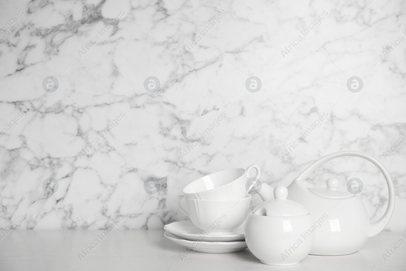 Photo of Set of clean tableware on white wooden table. Space for text