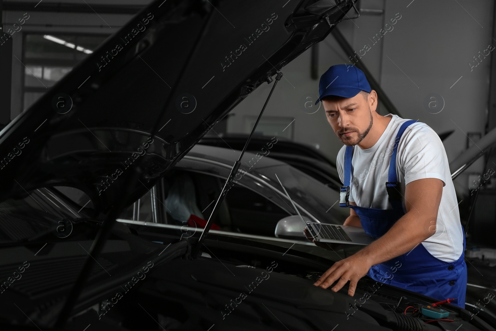 Photo of Mechanic with laptop doing car diagnostic at automobile repair shop