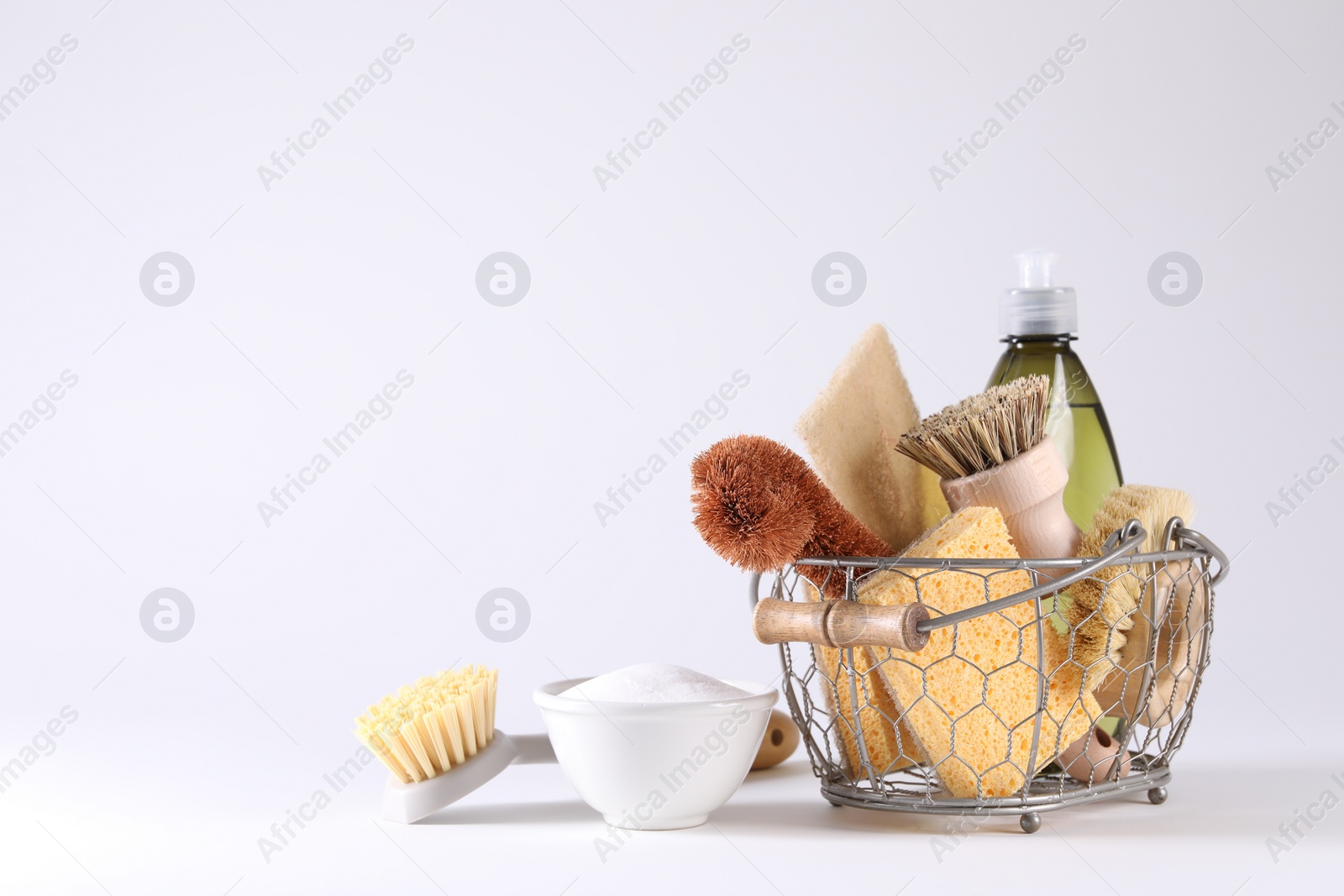 Photo of Set of different cleaning supplies in basket on white background