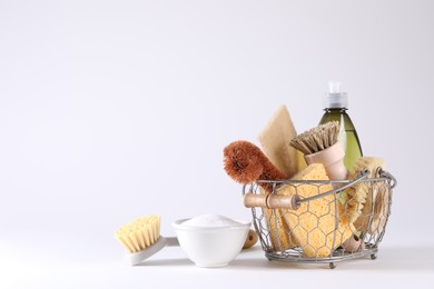 Photo of Set of different cleaning supplies in basket on white background