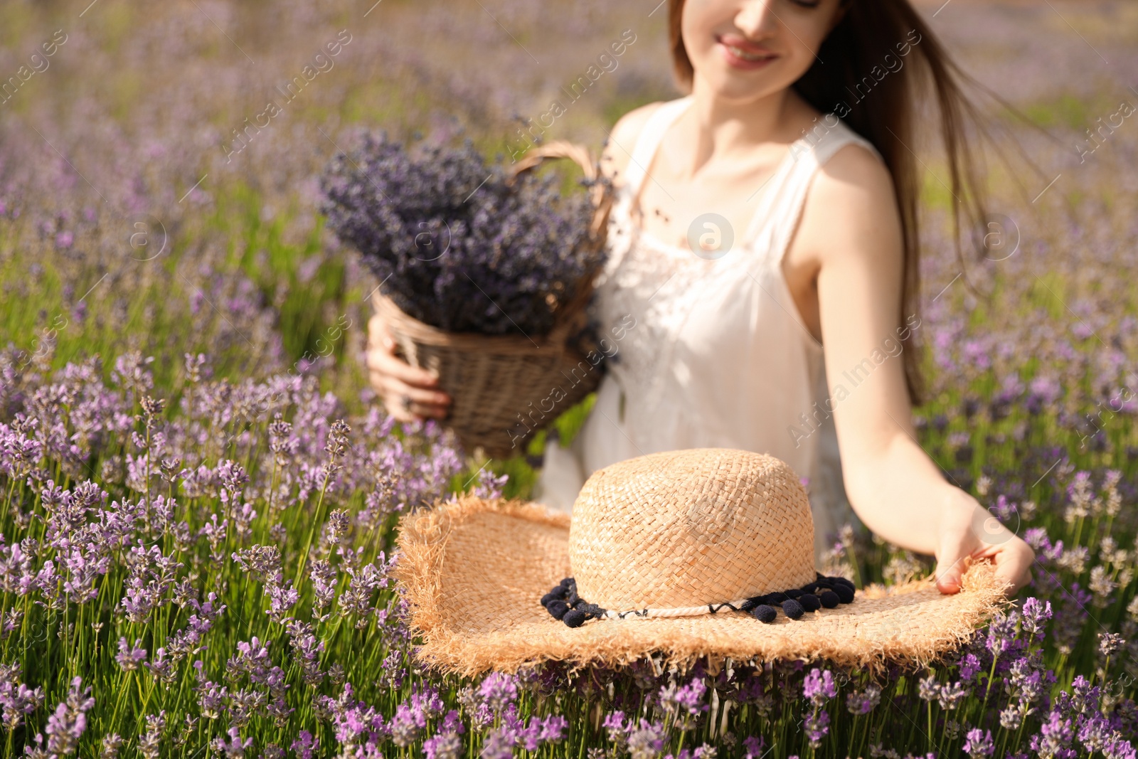 Photo of Young woman with straw hat in lavender field on summer day, closeup