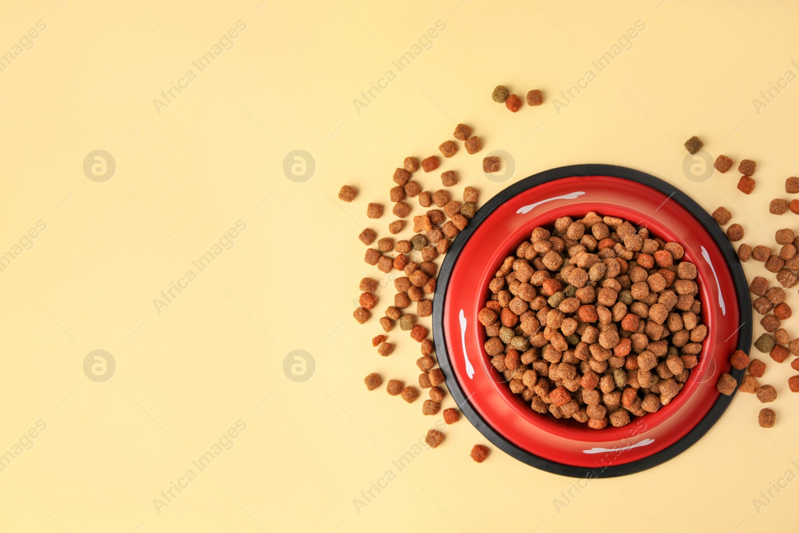 Photo of Dry dog food and feeding bowl on beige background, flat lay. Space for text