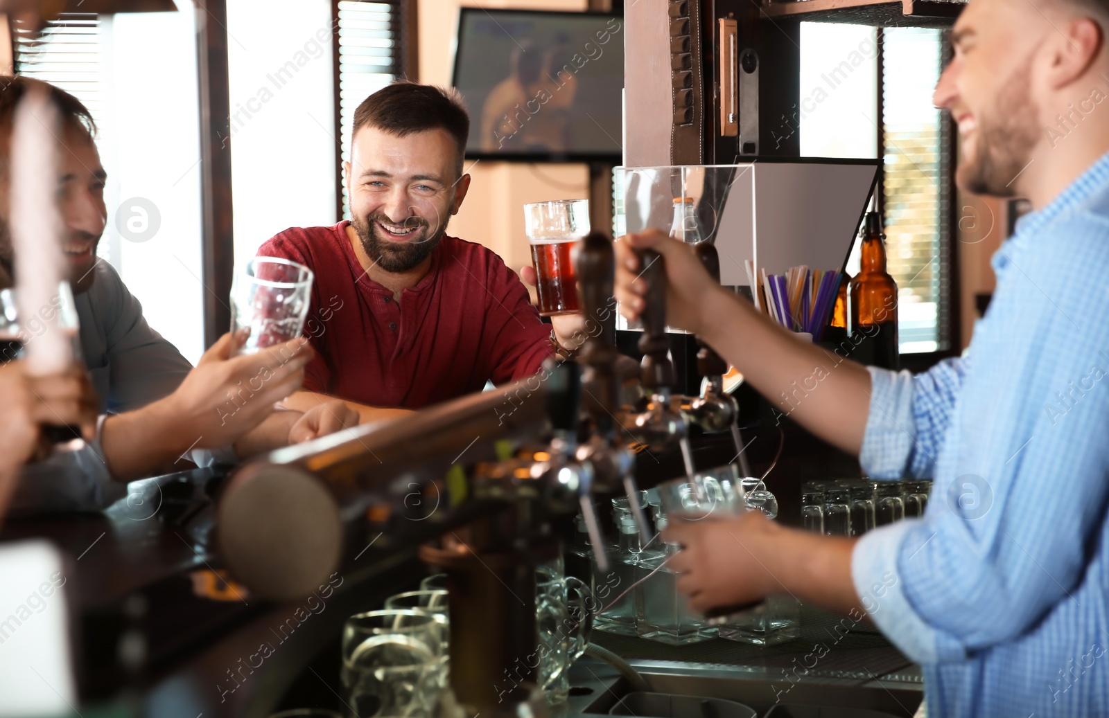 Photo of Friends drinking beer at counter in bar