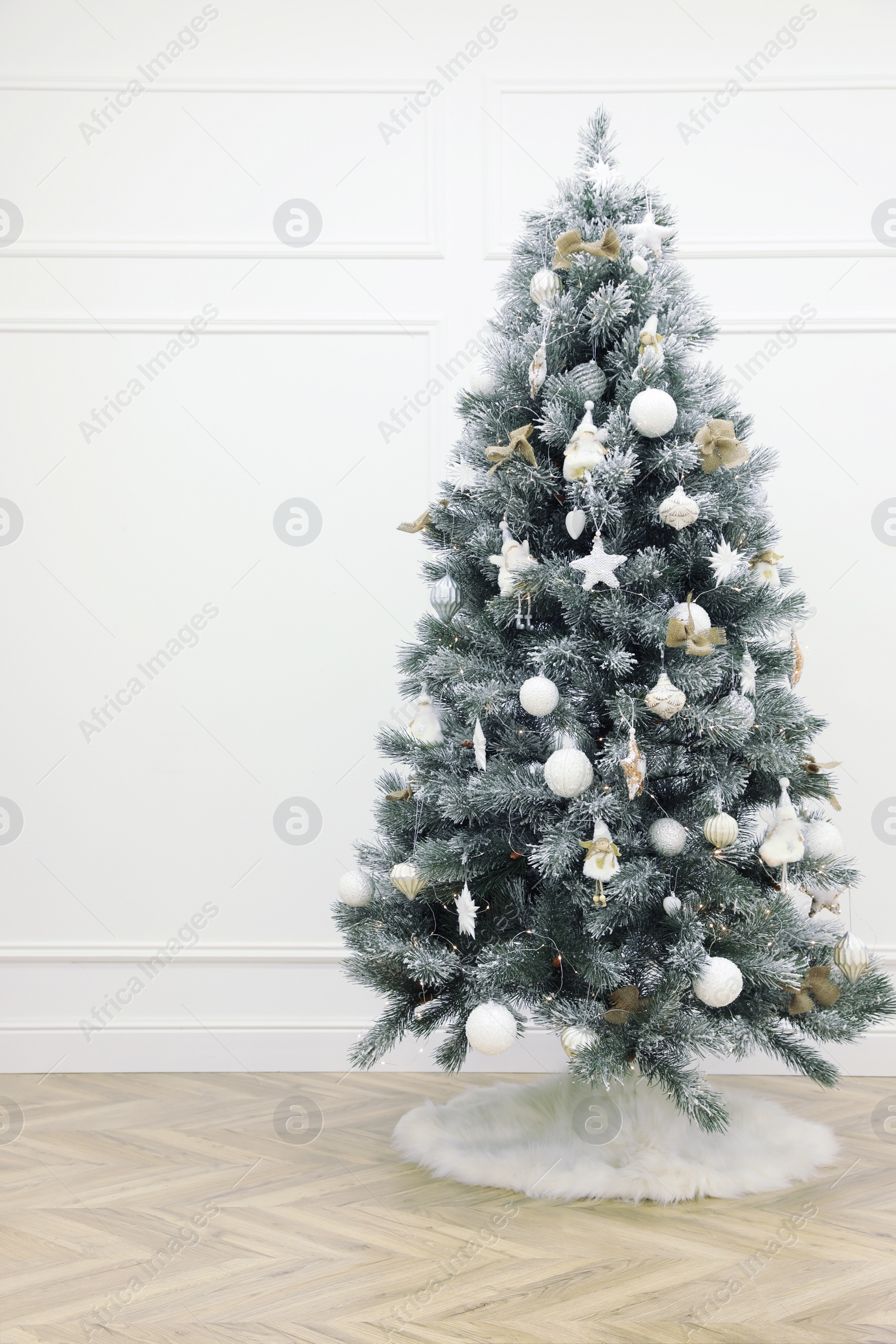 Photo of Beautiful decorated Christmas tree with skirt in room