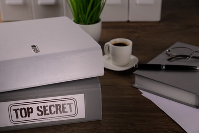 Image of Folder with documents and Top Secret stamp on wooden table, closeup