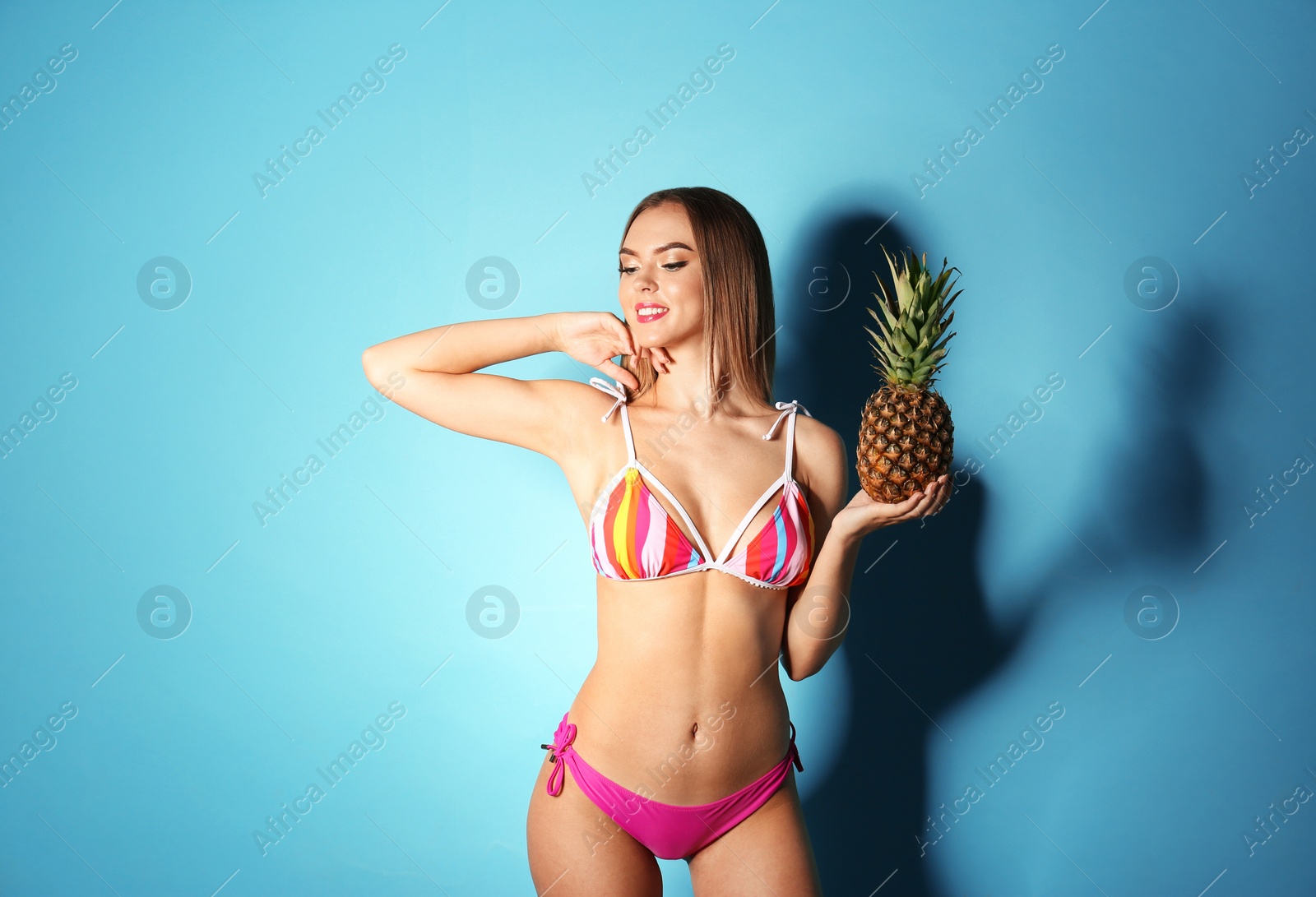 Photo of Pretty sexy woman in stylish bikini with pineapple on color background