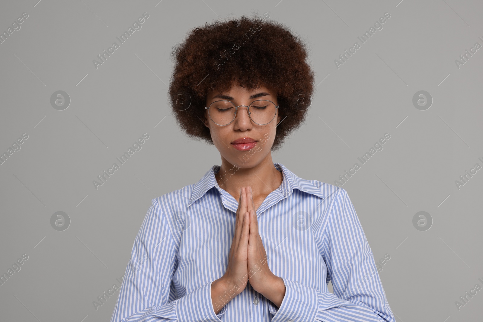 Photo of Woman with clasped hands praying to God on grey background