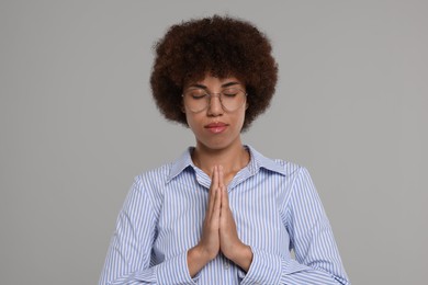 Photo of Woman with clasped hands praying to God on grey background