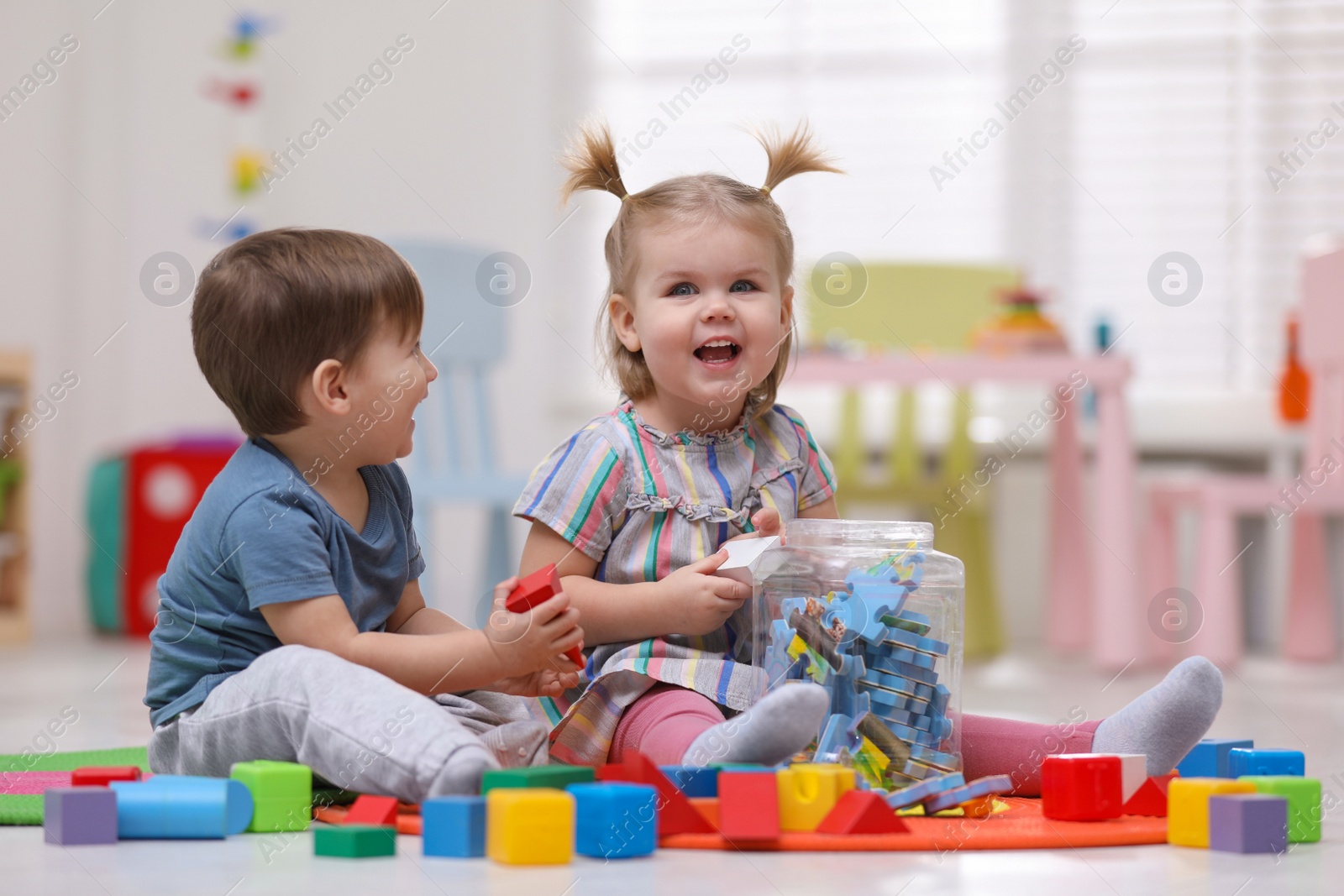 Photo of Cute little children playing together on floor at home