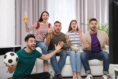 Group of friends watching football at home