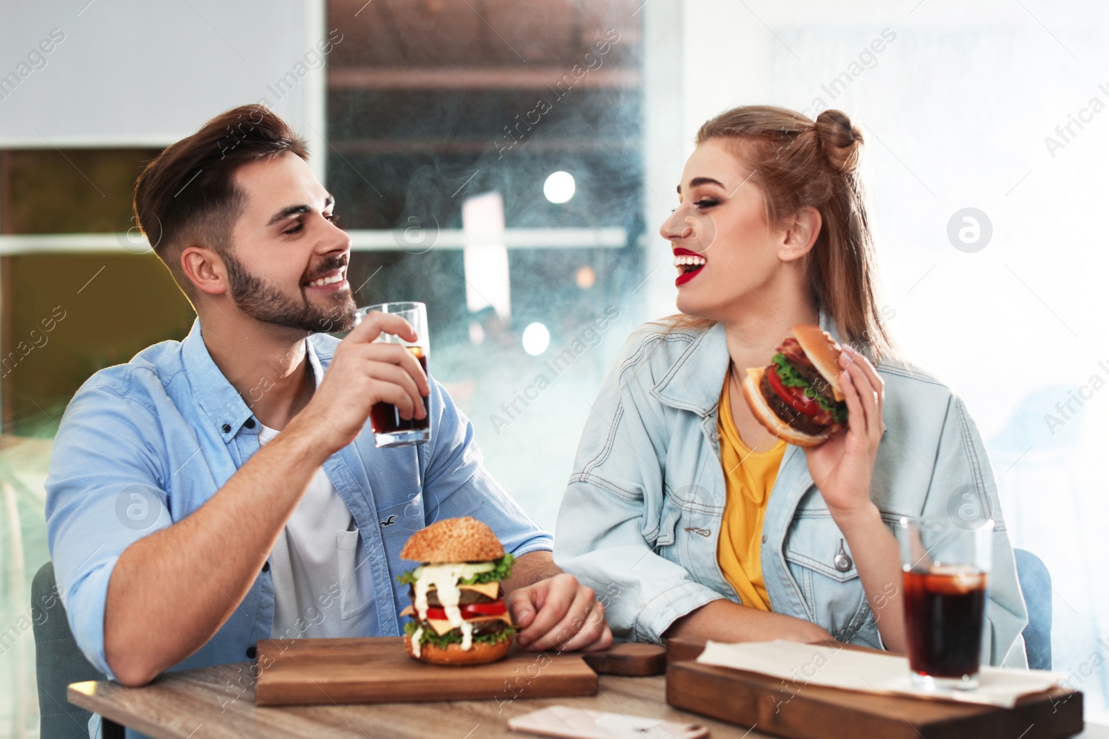 Photo of Happy young couple having lunch in burger restaurant