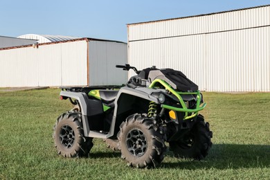 Photo of Modern quad bike in field near hangars on sunny day