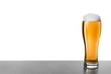 Photo of Glass of tasty beer on grey table against white background