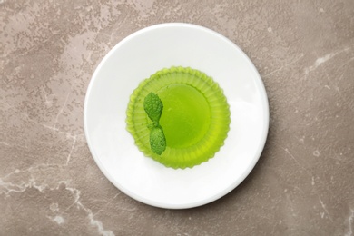 Plate with tasty fruit jelly and mint on beige table, top view