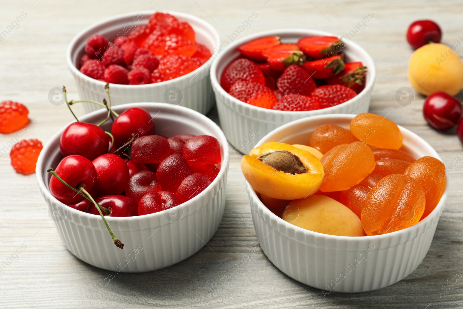 Photo of Delicious gummy candies and fresh fruits on white wooden table