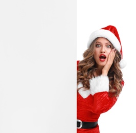 Photo of Beautiful Santa girl peeping out of blank banner on white background. Christmas celebration
