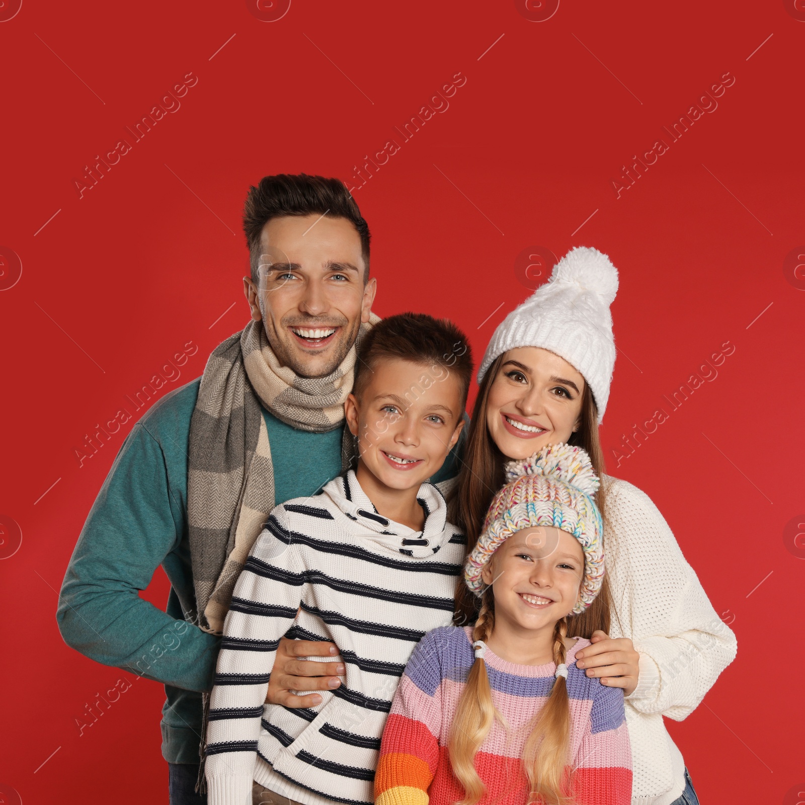 Photo of Happy family in warm clothes on red background. Winter season