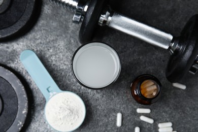 Photo of Amino acid shake, powder, pills and dumbbell on grey table, flat lay