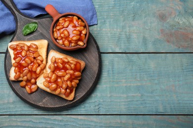 Photo of Toasts with delicious canned beans on light blue wooden table, top view. Space for text
