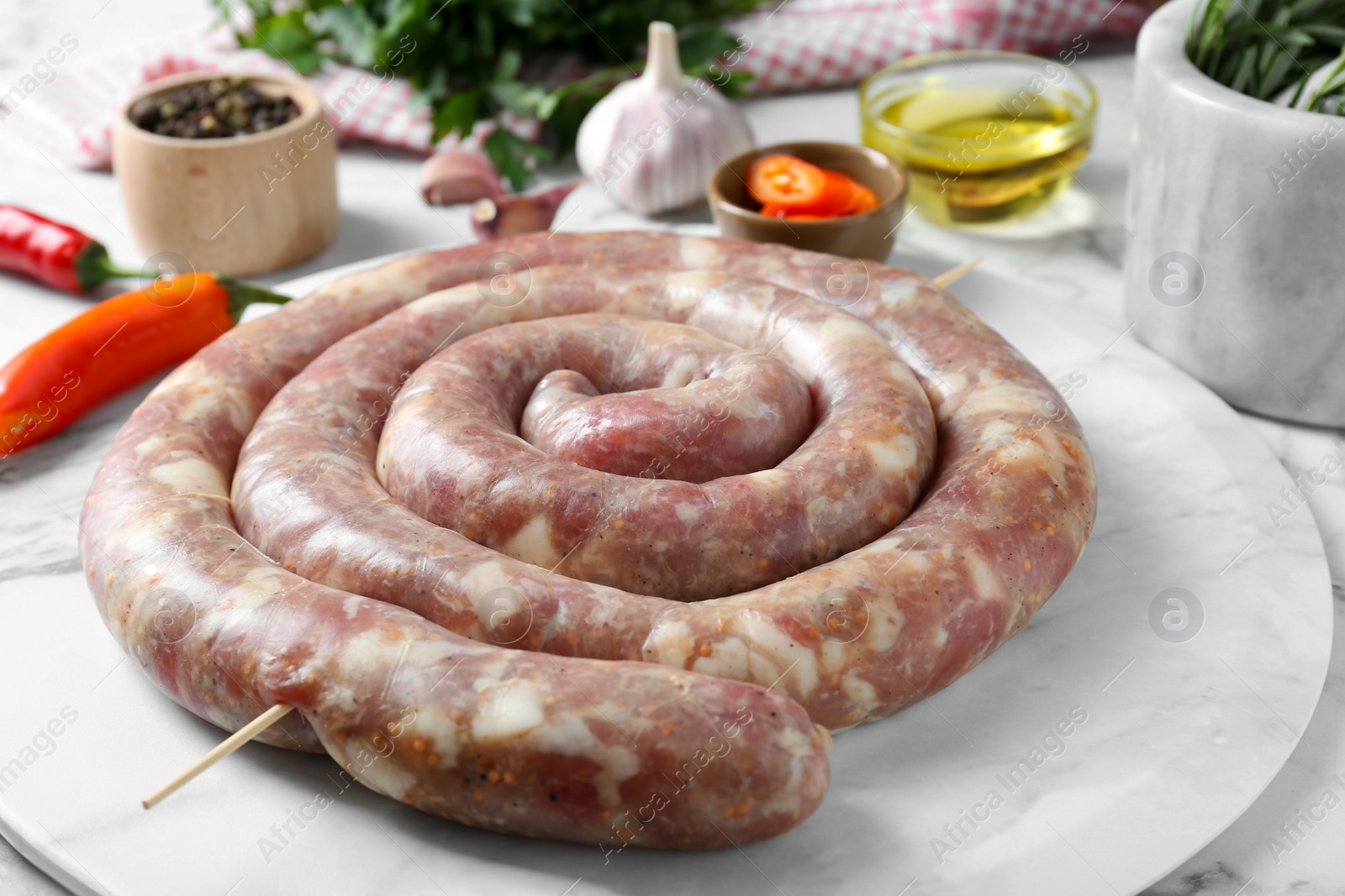 Photo of Raw homemade sausage on white marble table, closeup