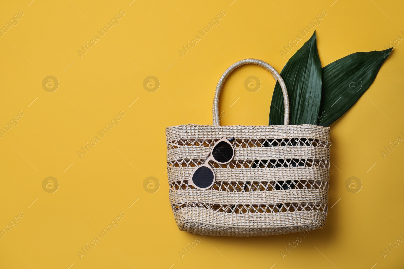 Photo of Stylish straw bag and sunglasses on yellow background, flat lay with space for text. Summer accessories