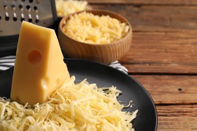 Photo of Grated and whole piece of cheese on wooden table, closeup. Space for text