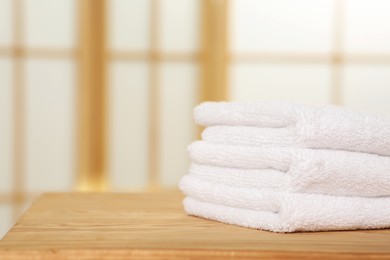 Photo of Soft folded terry towels on wooden table indoors, space for text