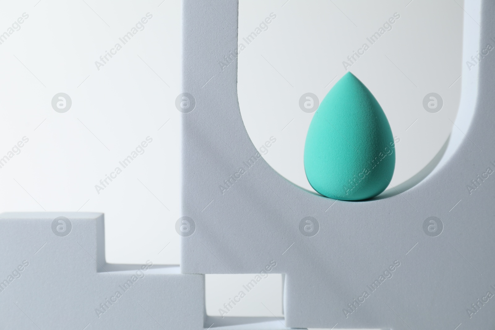 Photo of Stylish presentation of turquoise makeup sponge on white background