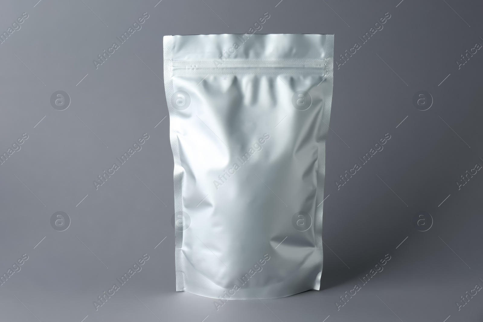 Photo of One blank foil package on grey background