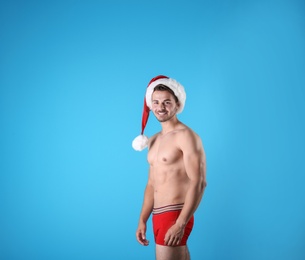 Shirtless young Santa Claus with sexy body on color background