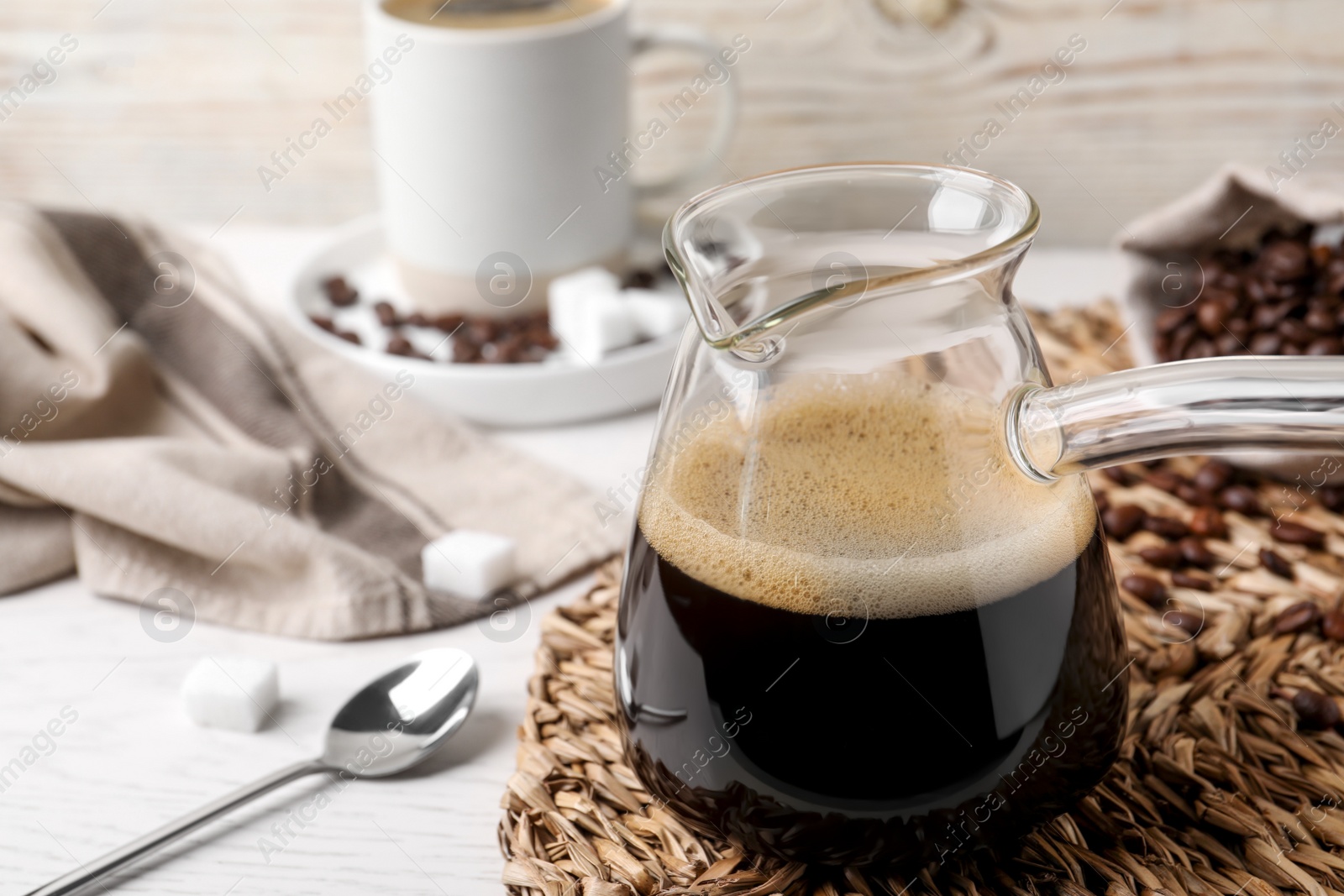 Photo of Turkish coffee. Glass cezve with hot aromatic coffee on white wooden table, space for text