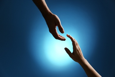 Man reaching for woman's hand on color background, closeup. Help and support concept