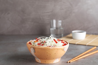 Bowl of noodles with vegetables on table. Space for text