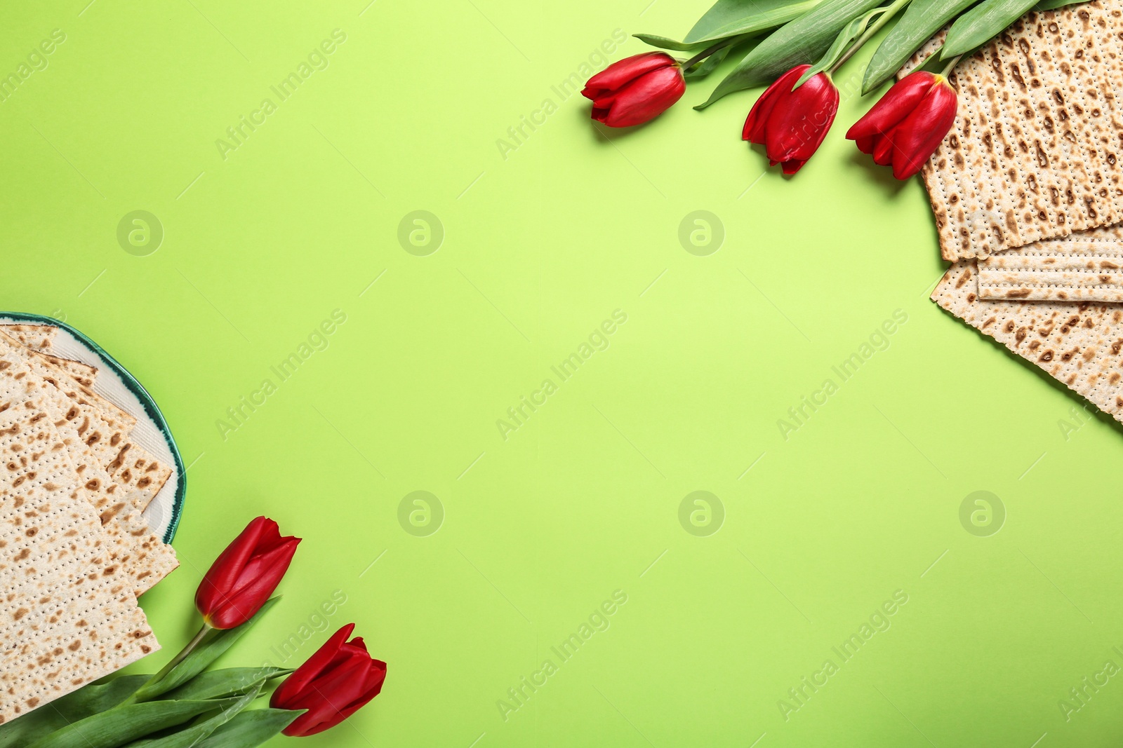 Photo of Tasty matzos and flowers on green background, flat lay with space for text. Passover (Pesach) Seder